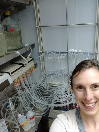 Caiti smiling at the camera with a lab bench in the background